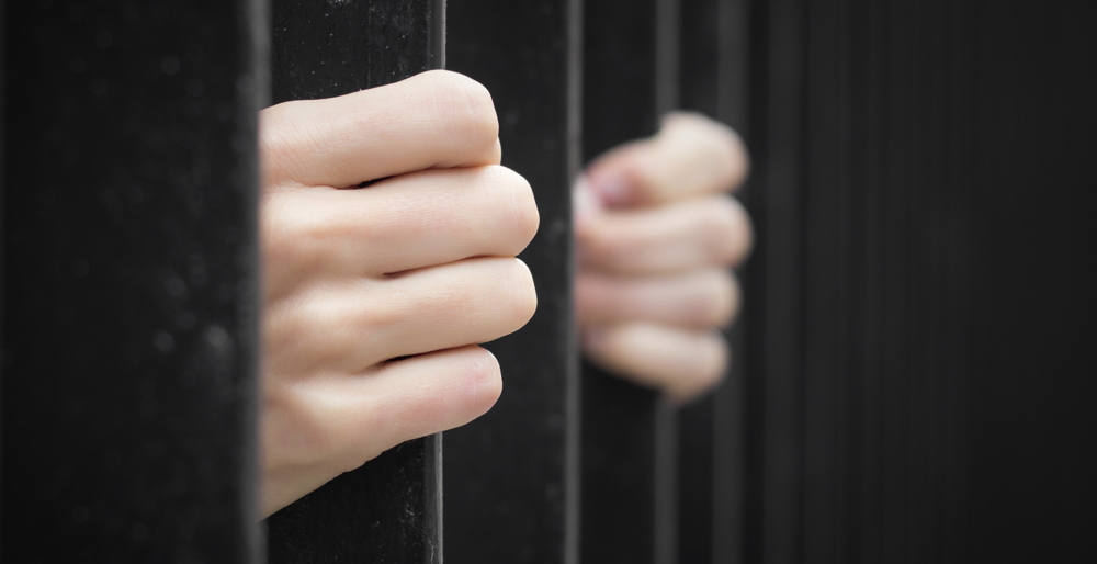prisoner-behind-jail-bars-000046978568_large