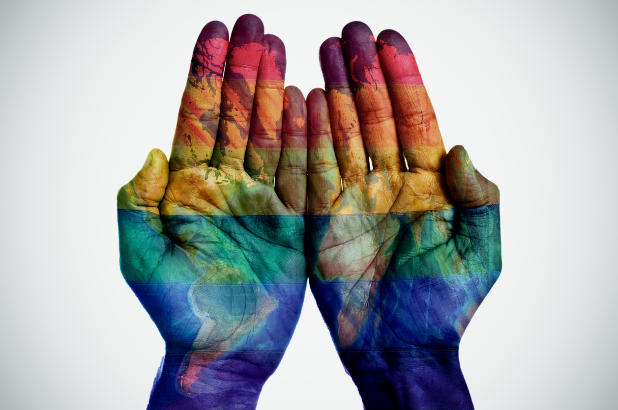 world-map-and-rainbow-flag-in-the-hands-539687252_1259x836